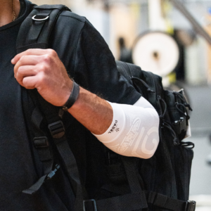 Close-up of a man wearing the white ELBOW Support Premier Padel brace on his arm